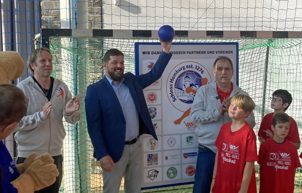 Kulturdezernent Felix Ammann (M.), Kulturamtsleiter Steffe Müller (l.) und der Vorsitzende des Handballkreises Oberberg, Udo Kolpe (r.) mit jungen Handballern beim symbolischen "Anwurf". Das Handballtor darf auch während der Ausstellung fleißig bespielt werden. (Foto: OBK)
