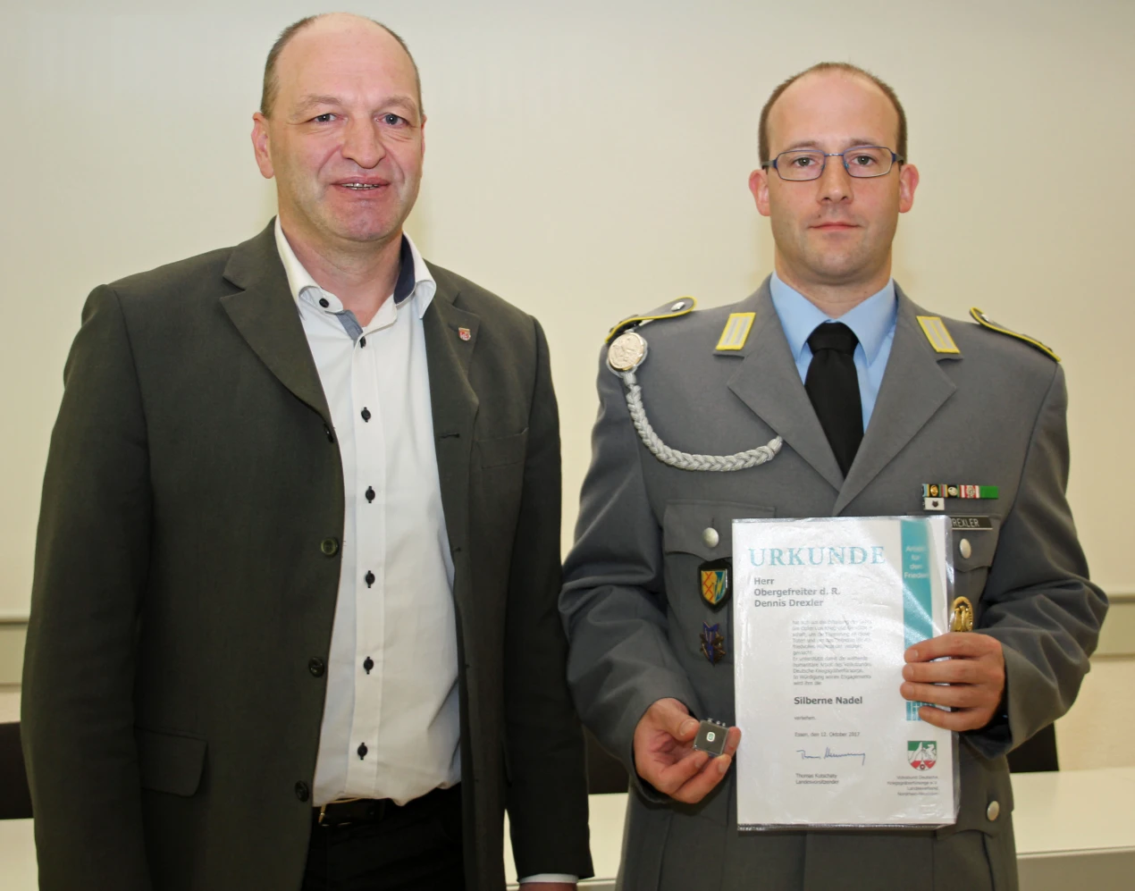 Wurde von der Ehrung überrascht: Dennis Drexler (r.) mit der Ehrenurkunde für seine Verdienste um den Volksbund Deutsche Kriegsgräberfürsorge, die ihm Andre Steiniger (Geschäftsführer des Kreisverbandes, l.) überreichte. (Foto: OBK)