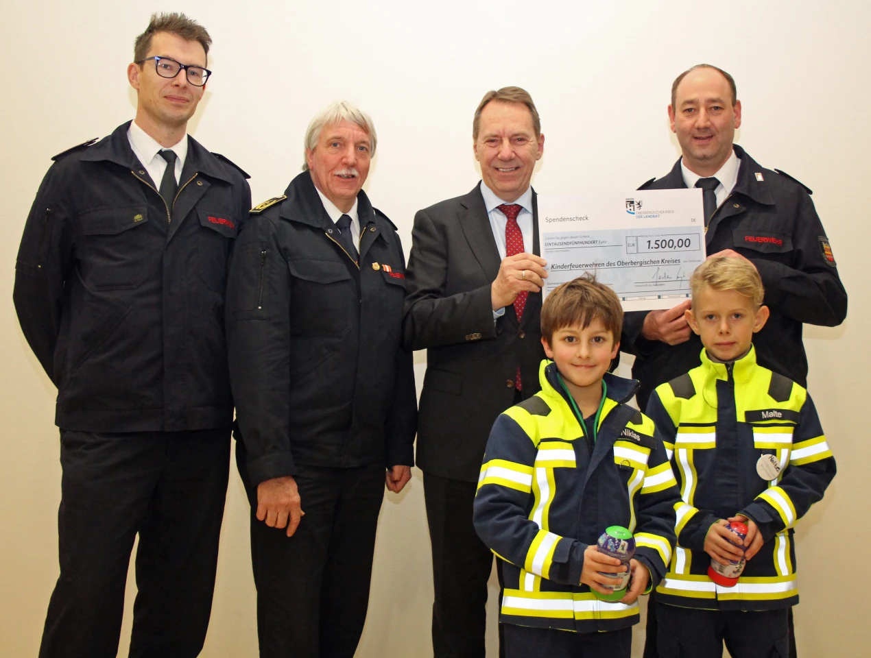 Die Vertreter der Kinderfeuerwehr Bergneustadt nahmen freudig ihren Scheck von Landrat Jochen Hagt und Kreisbrandmeister Wilfried Fischer (2.v.l.) entgegen: Jan Rothkamm (l.) und Michael Stricker (r.) die Leiter der Bergneustädter Kinderfeuerwehr mit den Nachwuchskräften Niklas Mießner und Malte Rothkamm. (Foto: OBK) 