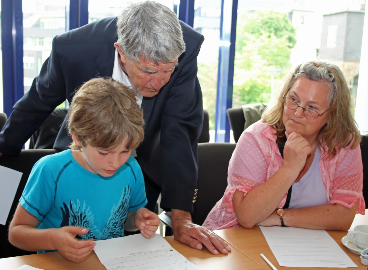 Marvin König ist in seinem Element. Der Viertklässler erklärt Prof. Wilke die Finalaufgaben der Matheolympiade. Der Rader Schüler wurde von seinen Eltern und seiner Tante Gabriele König (r.)zur Siegerehrung begleitet. (Foto: OBK)  