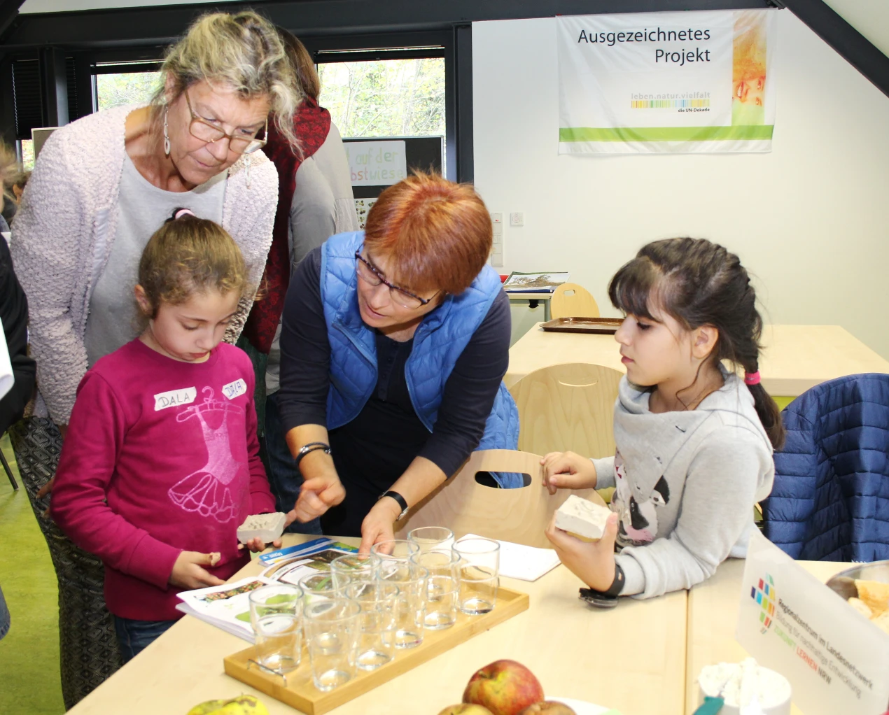 Birgit Pempera (l.) und Erika Waedt (r.) vom KI schauen den Kindern beim Füllen ihrer Wort-Hefte über die Schulter. (Foto: OBK)
